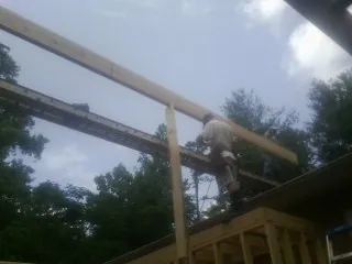 Carpenter setting a ridge beam over a new addition frame — Ice Dam Removal by Roofing Brothers in Coatesville